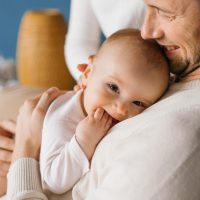 A happy young dad holds his six-month-old son in his arms